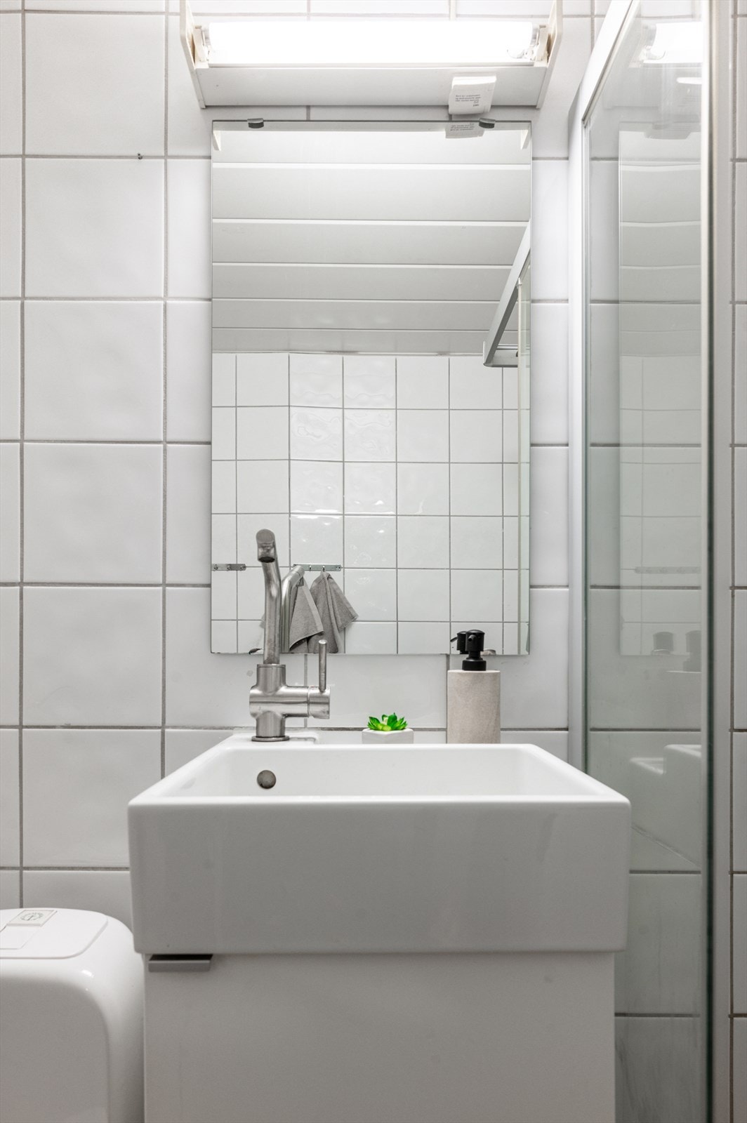 Badet er innredet med klosett, servant, samt et dusjhjørne med skyvbare glassdører. Galleribilde