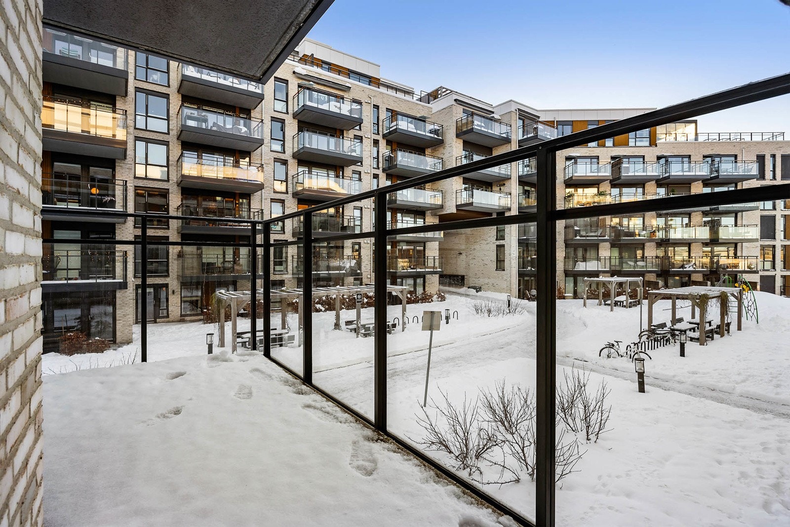 Balkongen vender mot frodig og hyggelig opparbeidet gårdsrom med sittegrupper og lekeplass for barn. Galleribilde