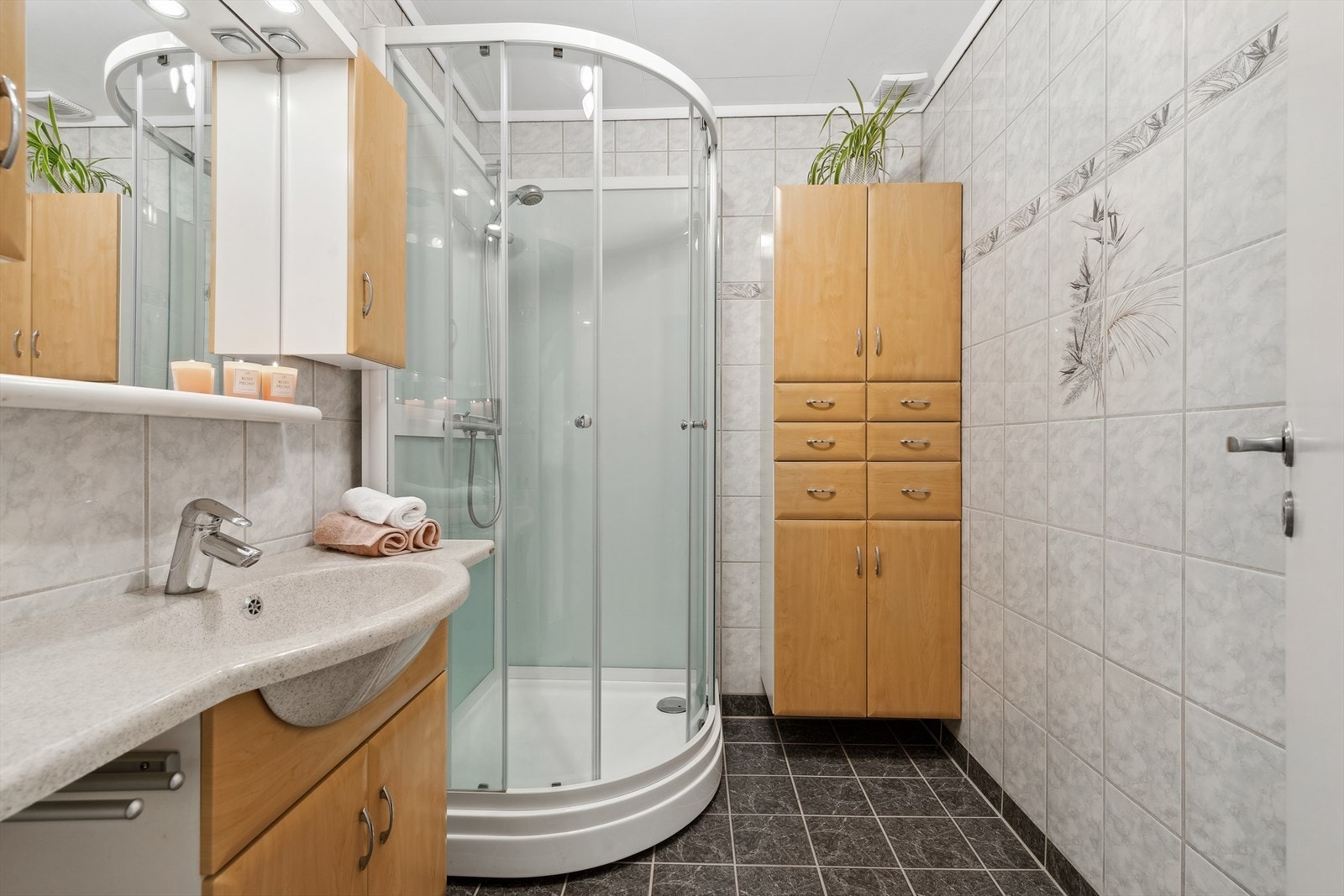 Flislagt baderom fra 2000 med elektriske varmekabler i gulv og himlingsplater i taket. Badet er utstyrt med nedfelt servant og dusjkabinett fra 2020. Det er elektrisk styrt vifte. Galleribilde