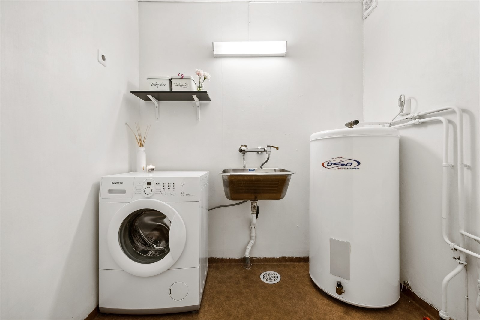 Vaskerom med vinylbelegg på gulv, våtromstapet/belegg på vegger og himlingsplater i taket. Vaskerommet er utstyrt med utslagsvask. Det er plass og opplegg for vaskemaskin. Varmtvannstanken er på ca. 200 liter fra 2000. Galleribilde