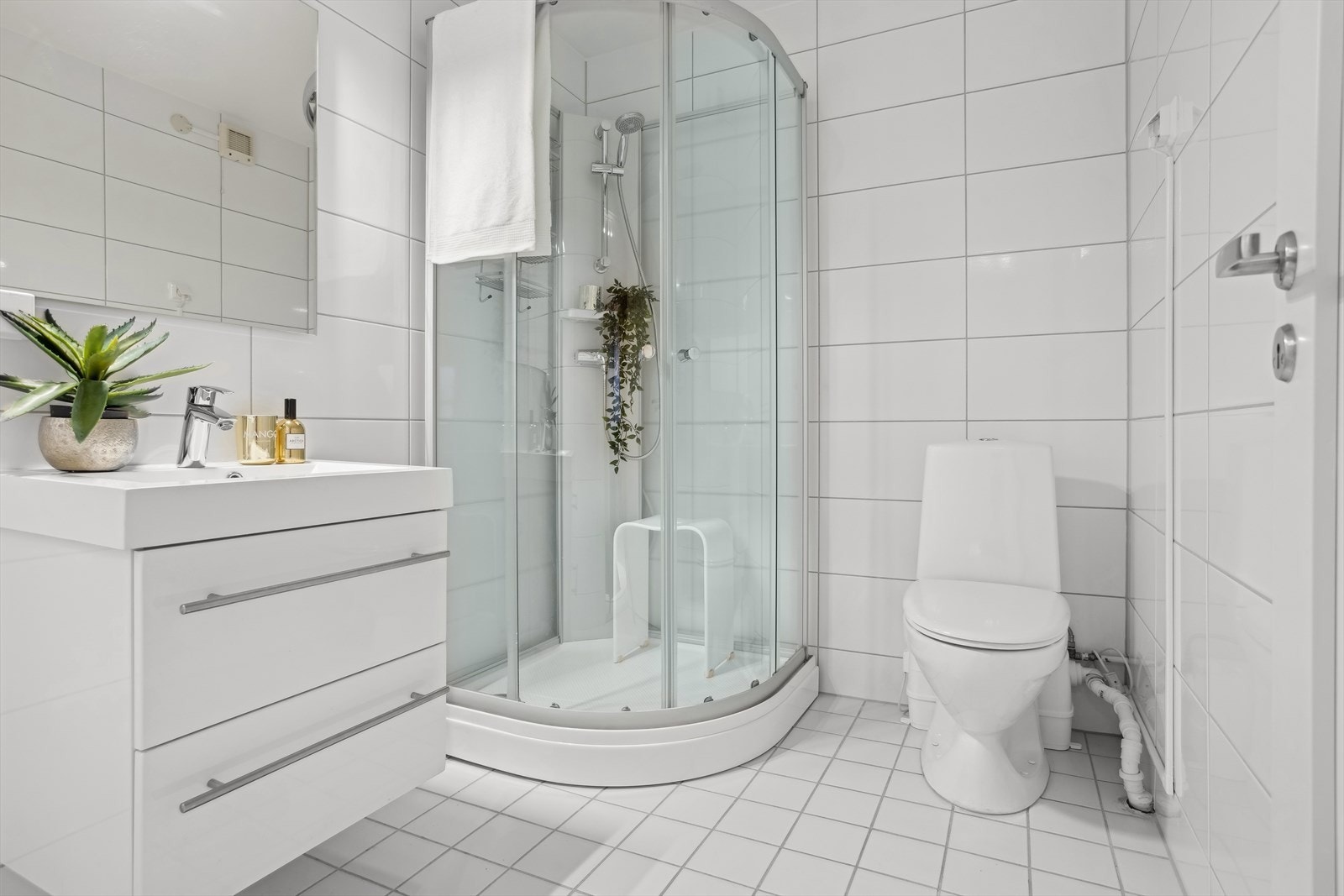 Baderommet har servant, oppbevaring, dusjkabinett, og toalett med kvern. Galleribilde