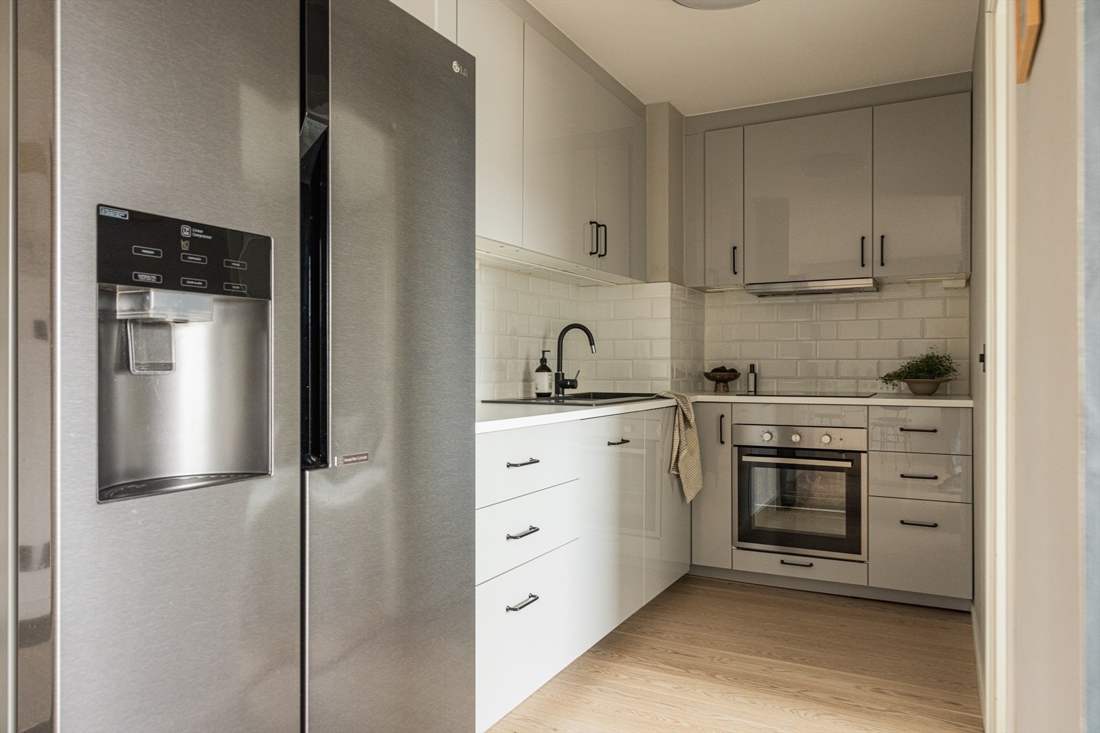 Kjøkkeninnredning med glatte fronter. Stekeovn, platetopp og oppvaskmaskin er integrert i innredningen. Galleribilde