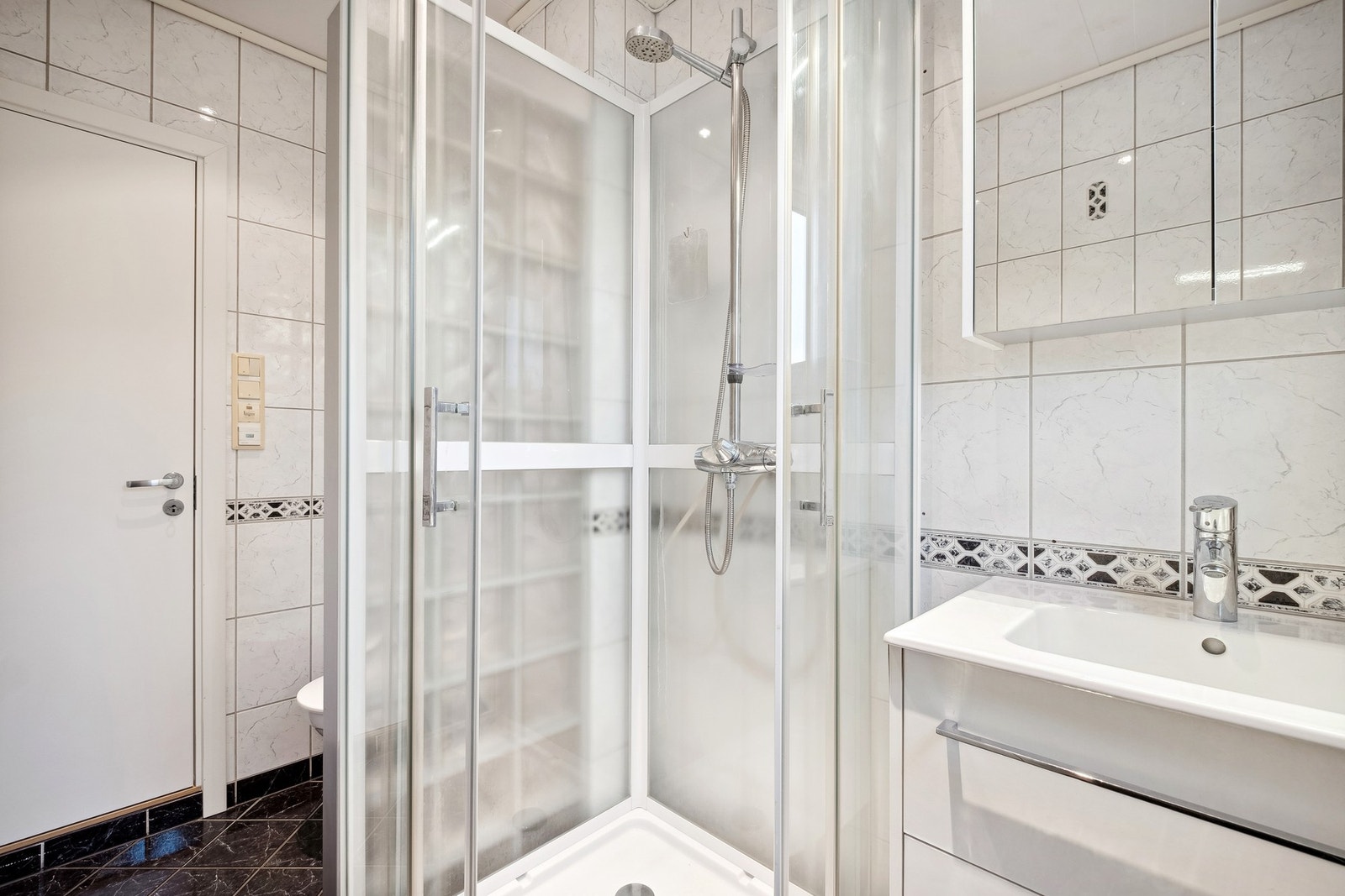 Tidløst flislagt bad med praktisk innredning og dusjkabinett. Badet er lokalisert i 2.etasje. Galleribilde