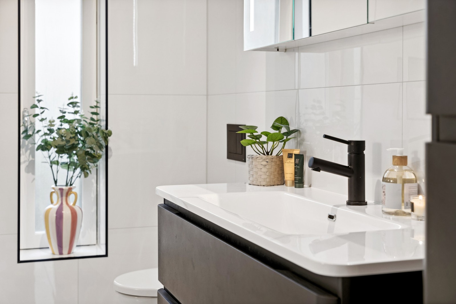 Badet er innredet med servant med underskap, veggskap og speilskap som gir godt med rom for oppbevaring av baderomsatrikkler. Galleribilde