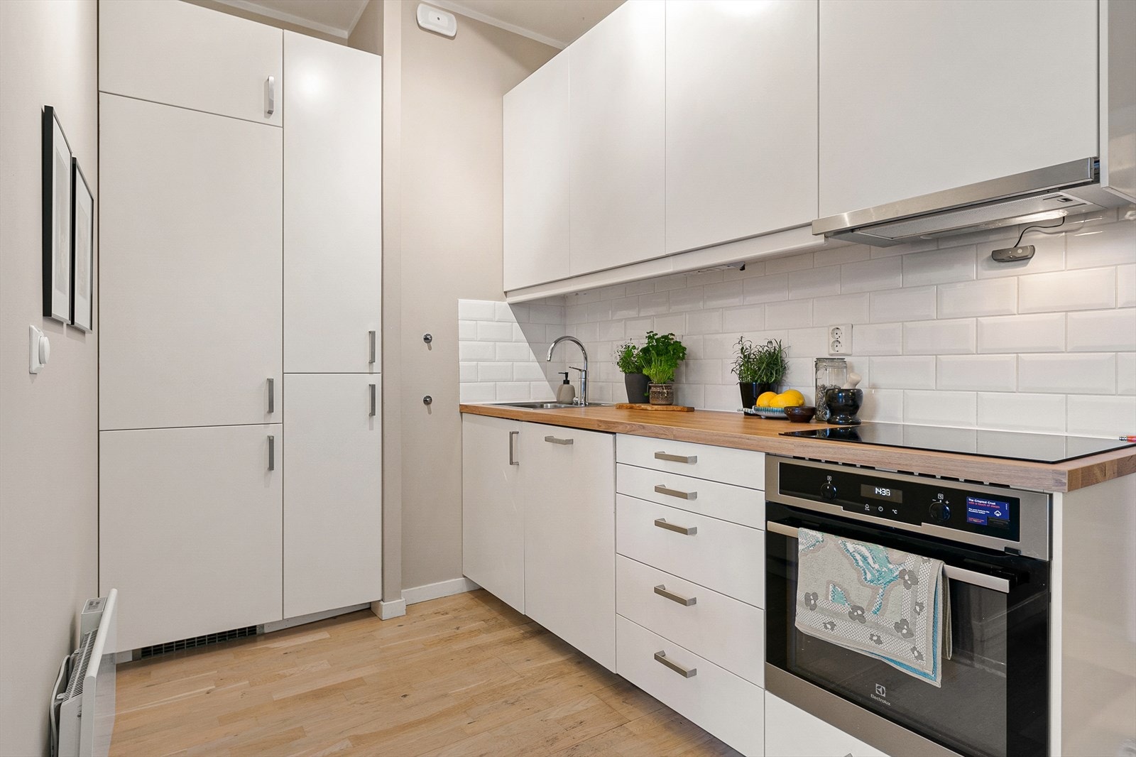 Kjøkkenet er praktisk plassert i det ene hjørnet av rommet. Innredningen har hvite, matte fronter og ny benkeplate. Det er godt med oppbevaringsplass i skuffer og skap som gjør det enkelt å holde orden. Galleribilde