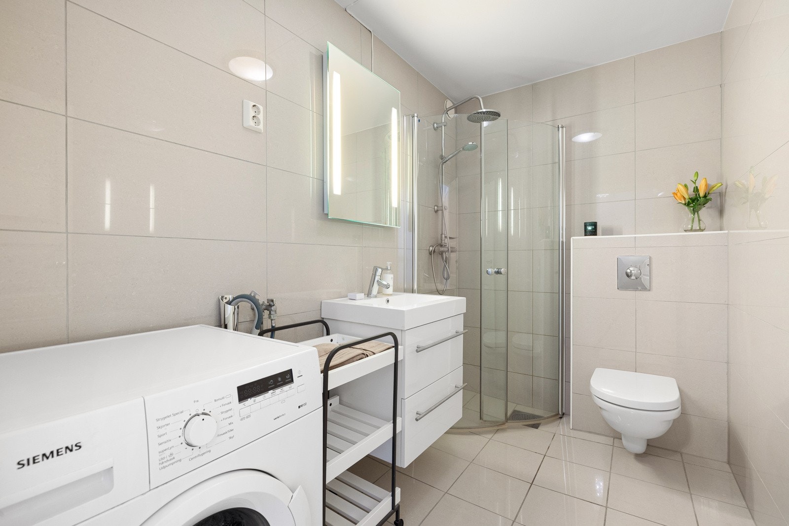 Delikat flislagt baderom med varmekabler og opplegg for vaskemaskin. Galleribilde