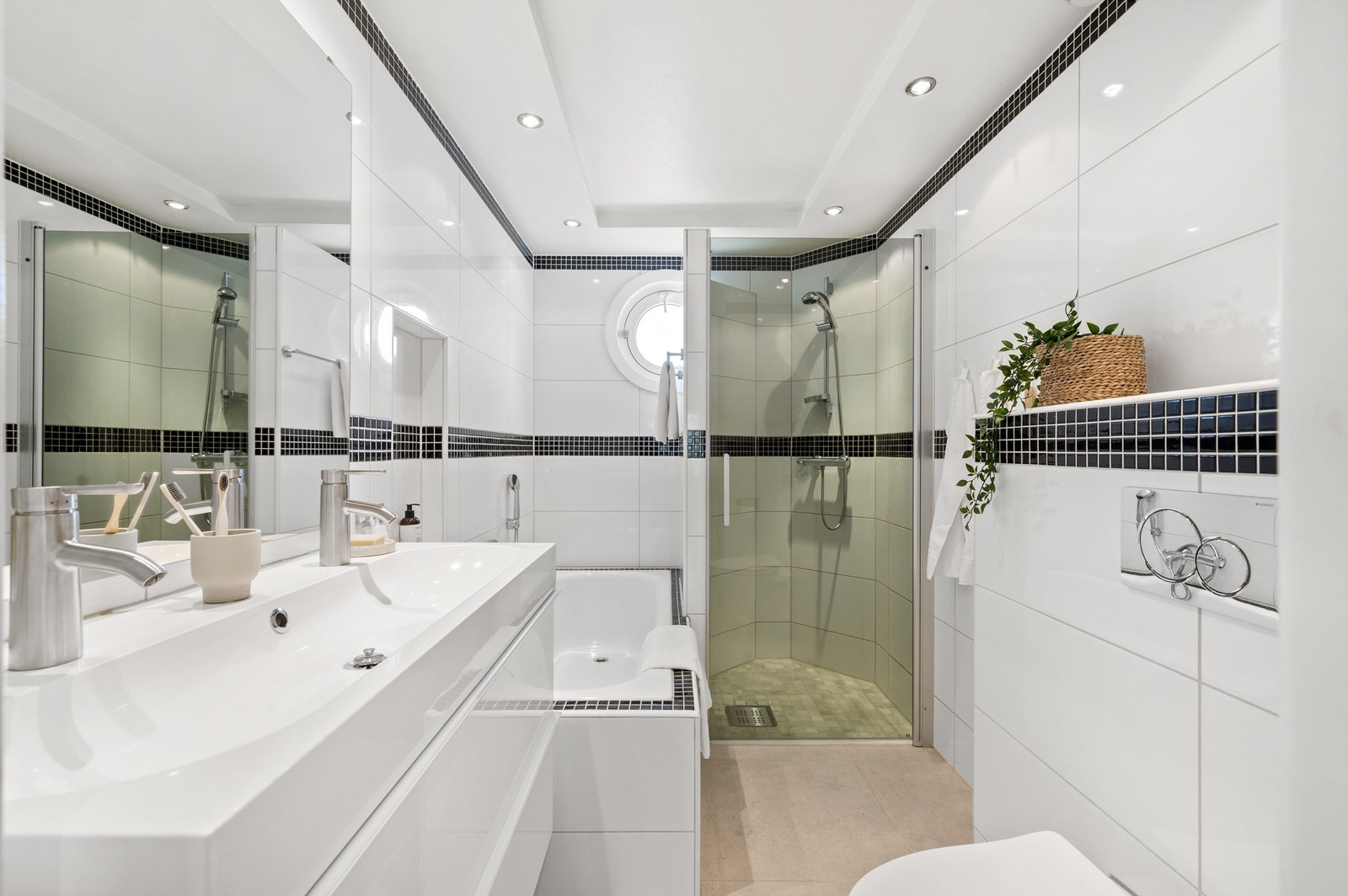 Leilighetens bad er pent flislagt på gulv og vegger, med gulvvarme Galleribilde