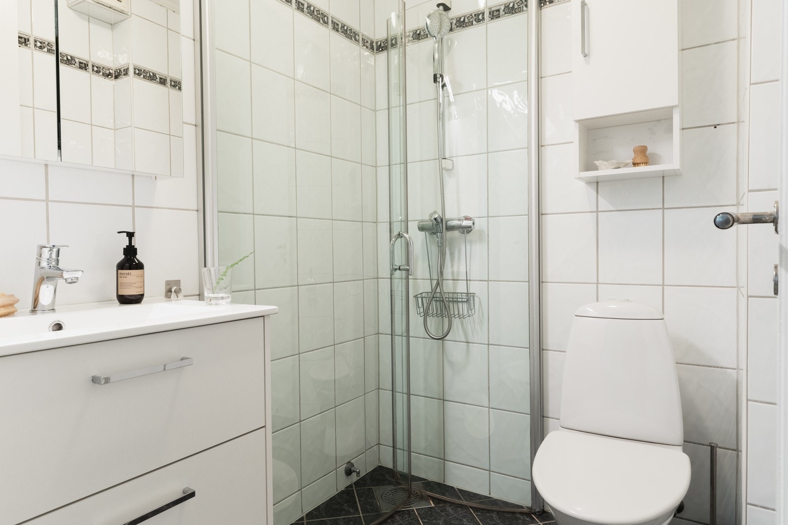 Badet er helfliset og har varmekabler i gulv. Badet er innredet med dusj med glassvegger, toalett og baderomsinnredning. Galleribilde