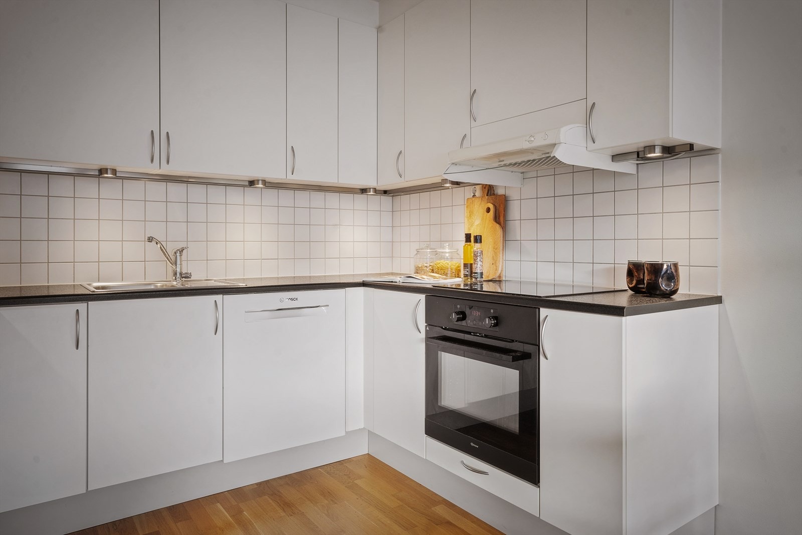 Kjøkkenet har pen innredning med hvite fronter, fliser på bakvegg og laminert benkeplate. Galleribilde