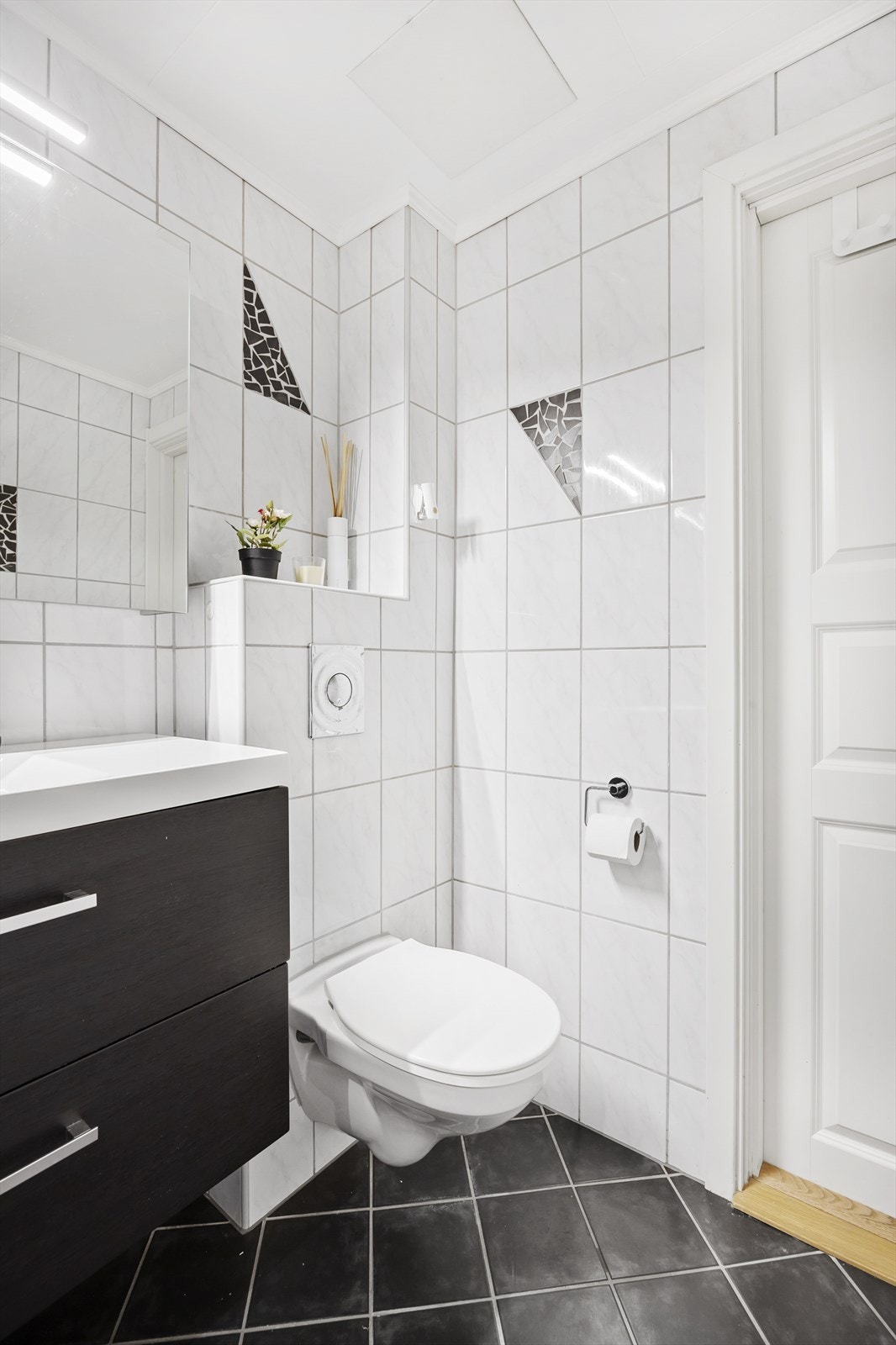 Videre er badet utstyrt med dusjhjørne med skyvedør, vegghengt wc og servantinnredning fra 2020, med skuffer og overskap Galleribilde