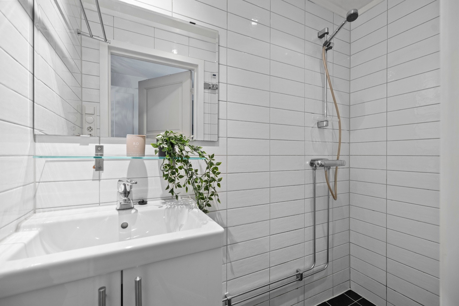 Flislagt dusjbad med varmekabler som er innredet med gulvstående servantskap med heldekkende vask og ett-greps armatur i krom Galleribilde