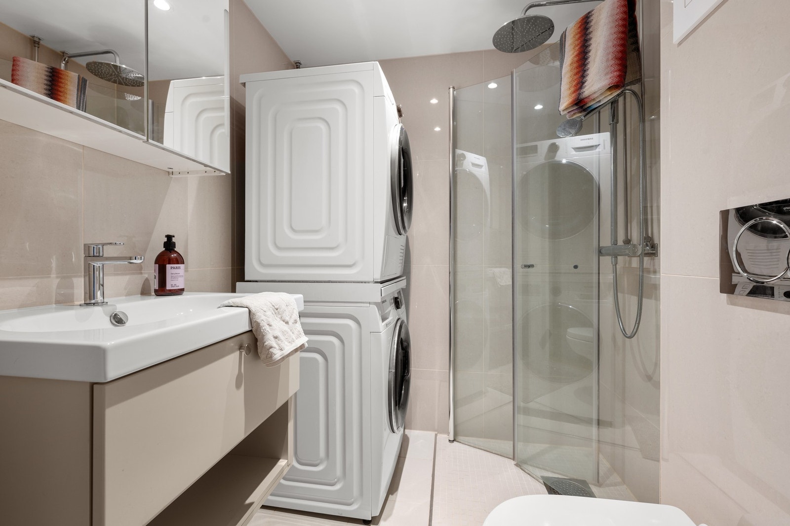 Lekkert og godt utnyttet bad med stilren innredning og fliser, samt dusj med innfellbare glassdører og opplegg for vaskemaskin og tørketrommel. Galleribilde