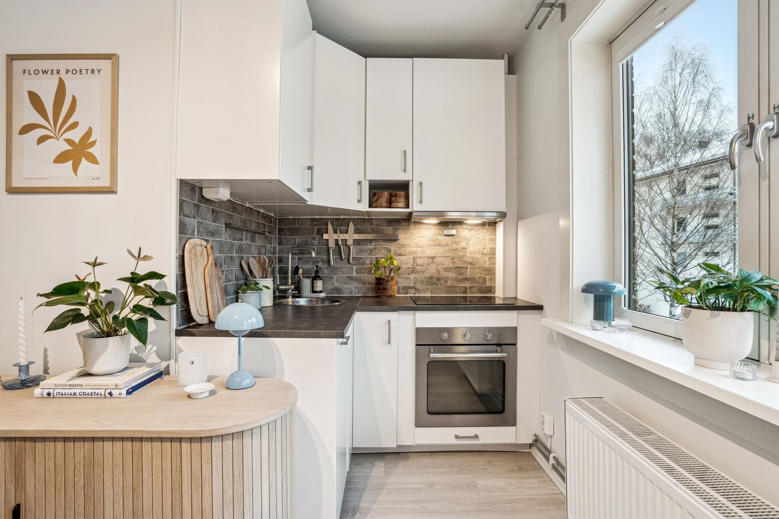 Åpen kjøkkenløsning mot stuen med integrerte hvitevarer som komfyr med platetopp, oppvaskmaskin og kjøleskap. Galleribilde