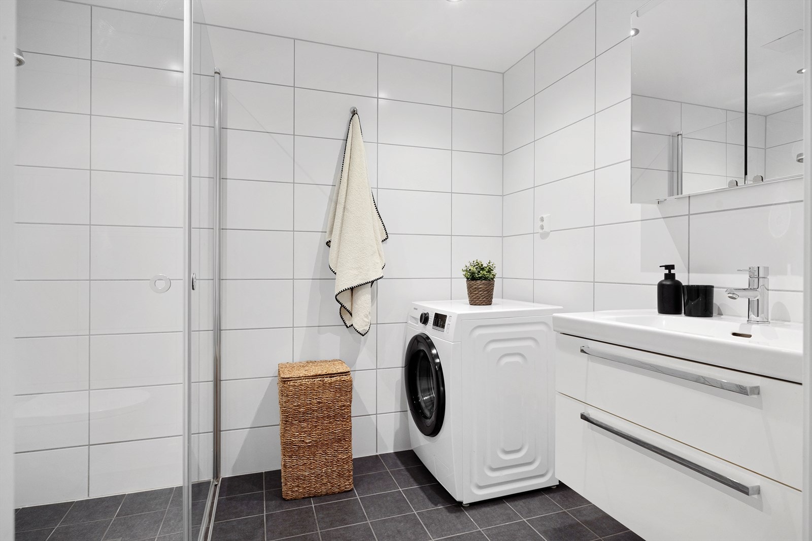 Pent flislagt baderom med gulvvarme og downlights i himlingen. Badet er utstyrt med servantskap med servant, veggskap med speil og belysning over, samt veggmontert klosett. Galleribilde