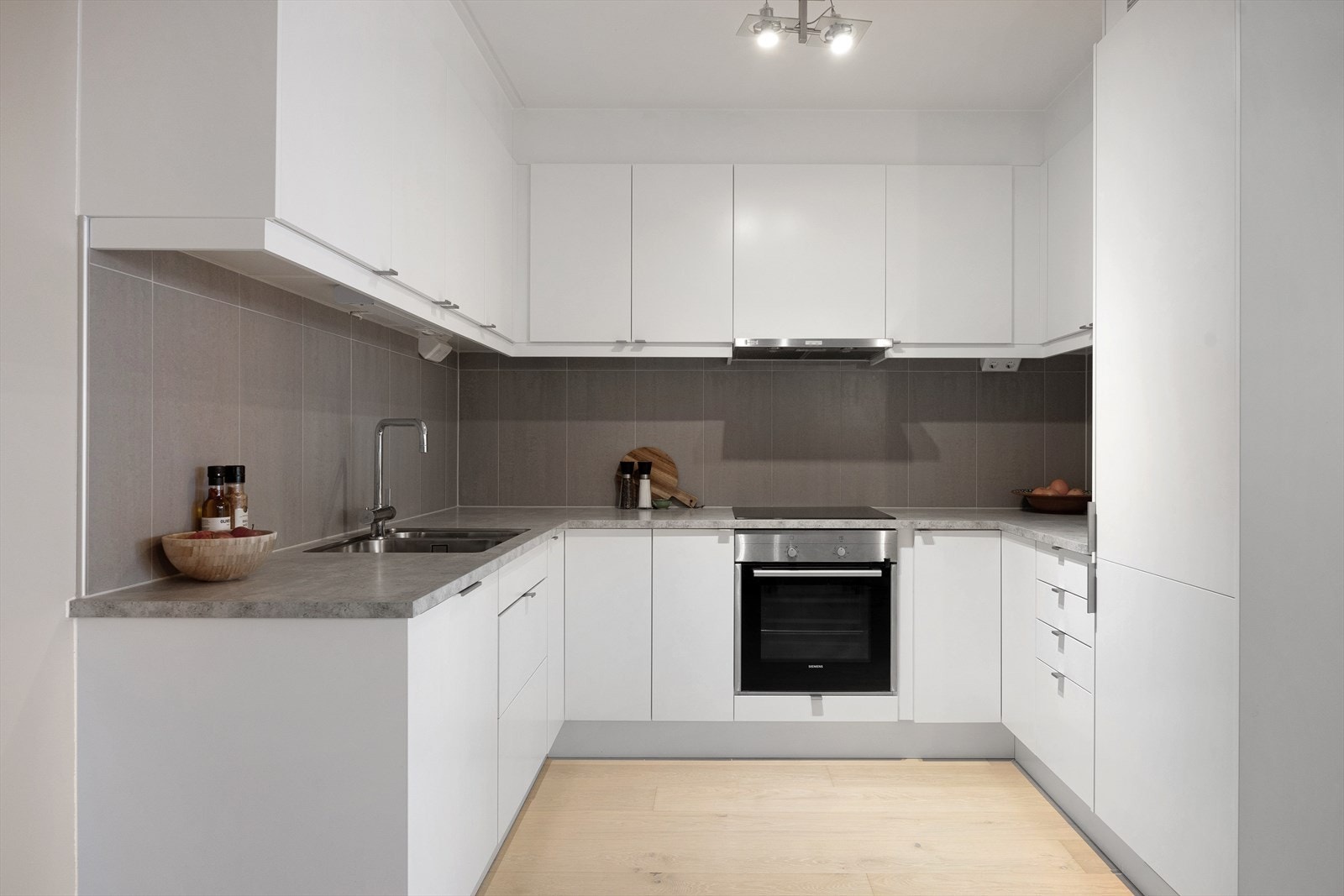 Kjøkkenet har glatte fronter og laminatbenkeplate med nedfelt oppvaskkum og ettgreps, svingbart blandebatteri. Innredningen består av både over- og underskap, med belysning under overskapene. Galleribilde