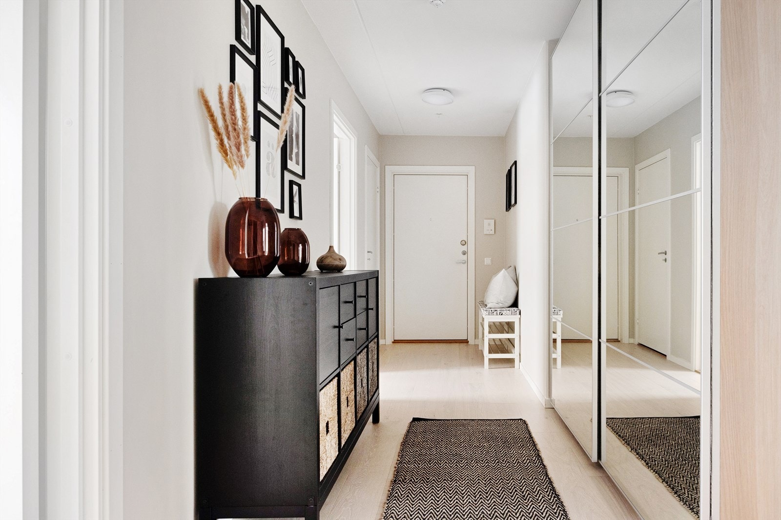 Velkommen inn! Leiligheten ønsker deg velkommen med en lys og innbydende entré som gir et strålende førsteinntrykk. Her finner du en romslig skyvedørsgarderobe med speildører, som tilbyr rikelig med oppbevaringsplass for yttertøy og sko. Galleribilde