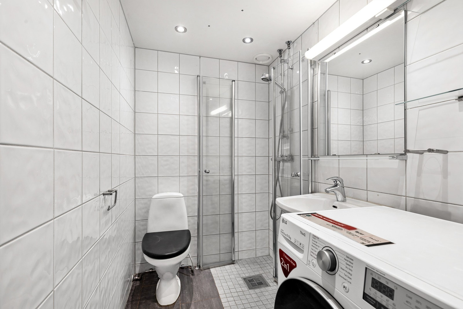 Badet har dusjhjørne med foldedører av glass Galleribilde