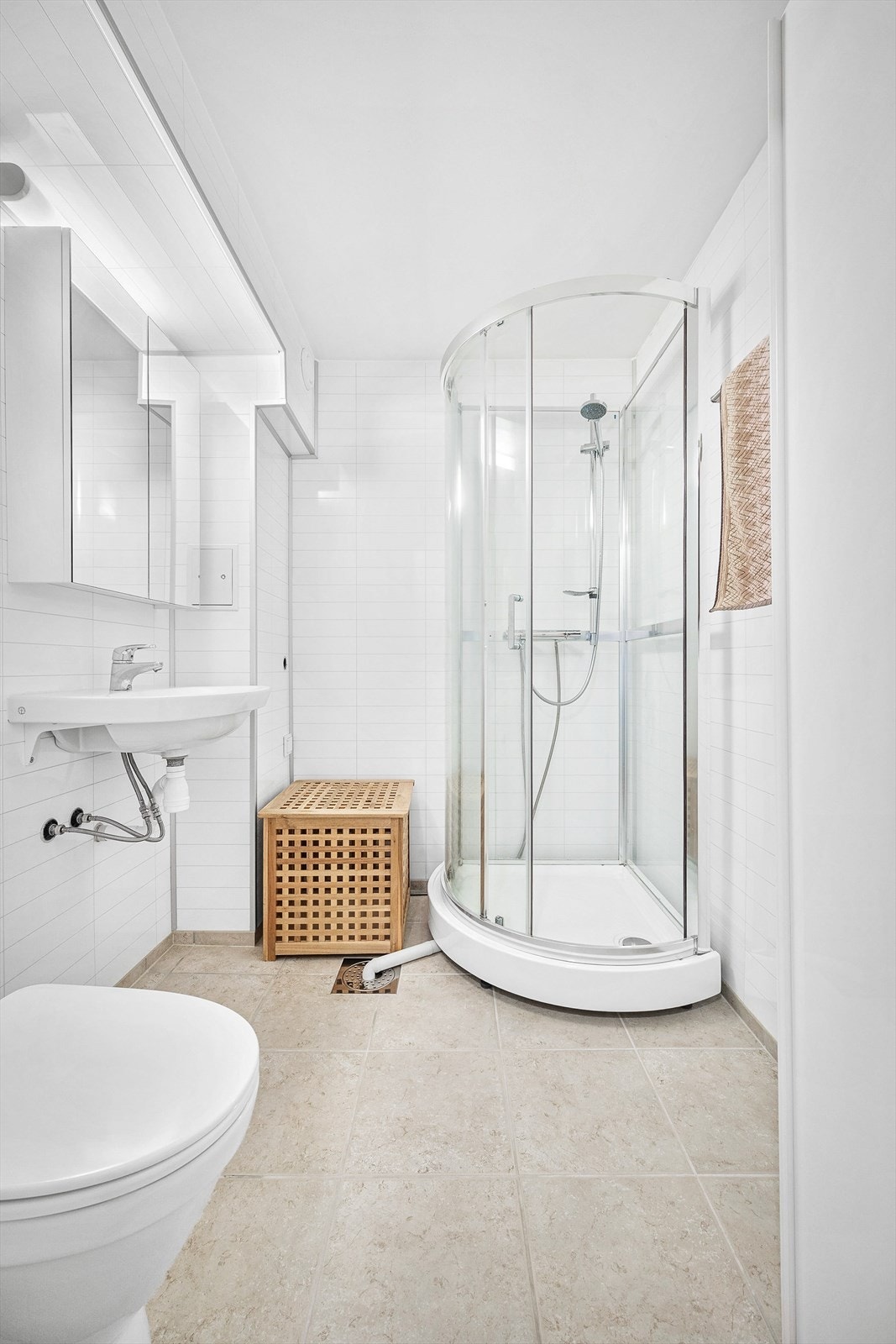 Badet er utstyrt med vegghengt servant, speilskap med overlys dusjkabinett og gulvstående toalett Galleribilde