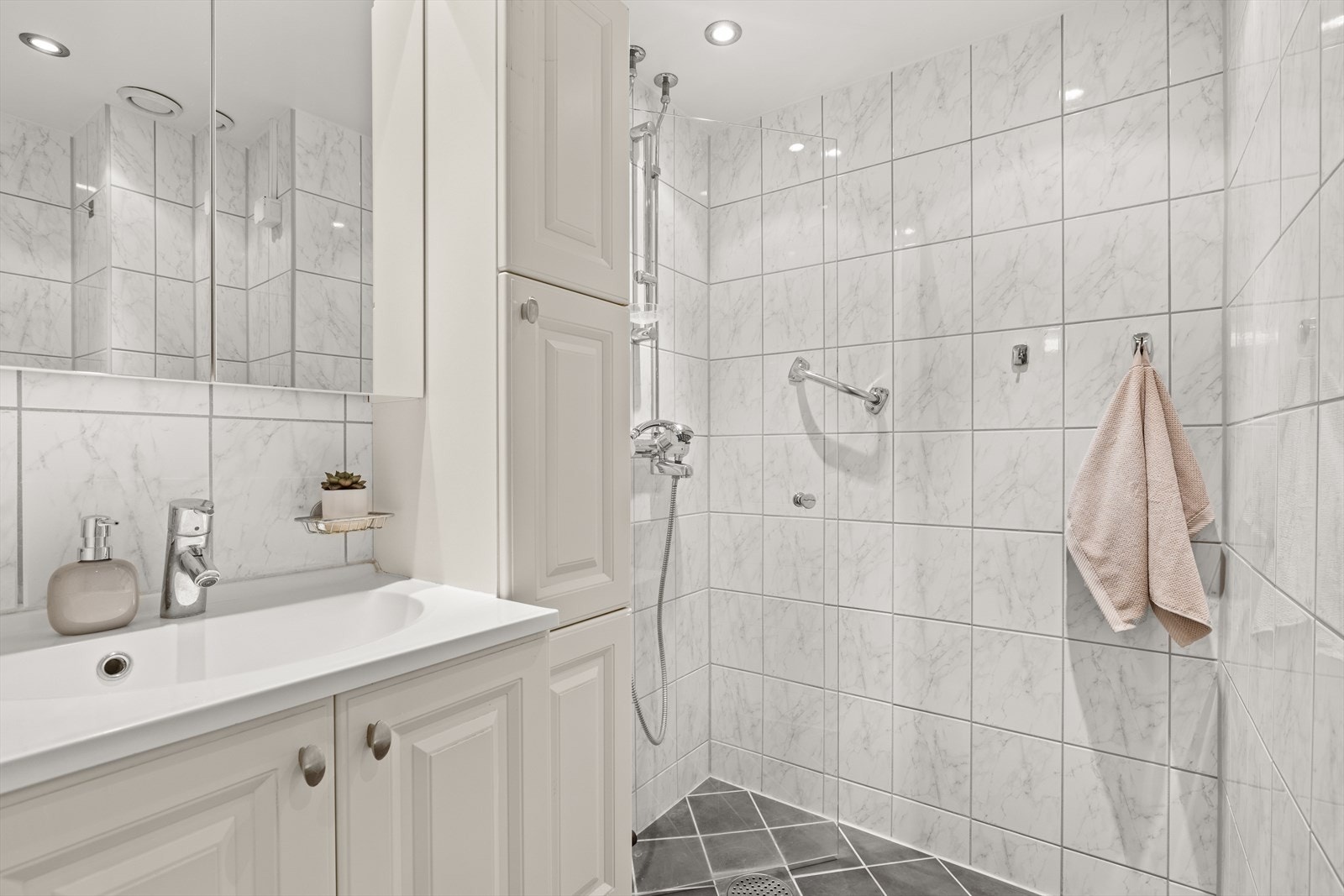 Badet er av god størrelse med dusjhjørne, servant med innredning, toalett og klargjort opplegg for vaskemaskin. Badet har også varmekabler i gulv og downlights i himling Galleribilde