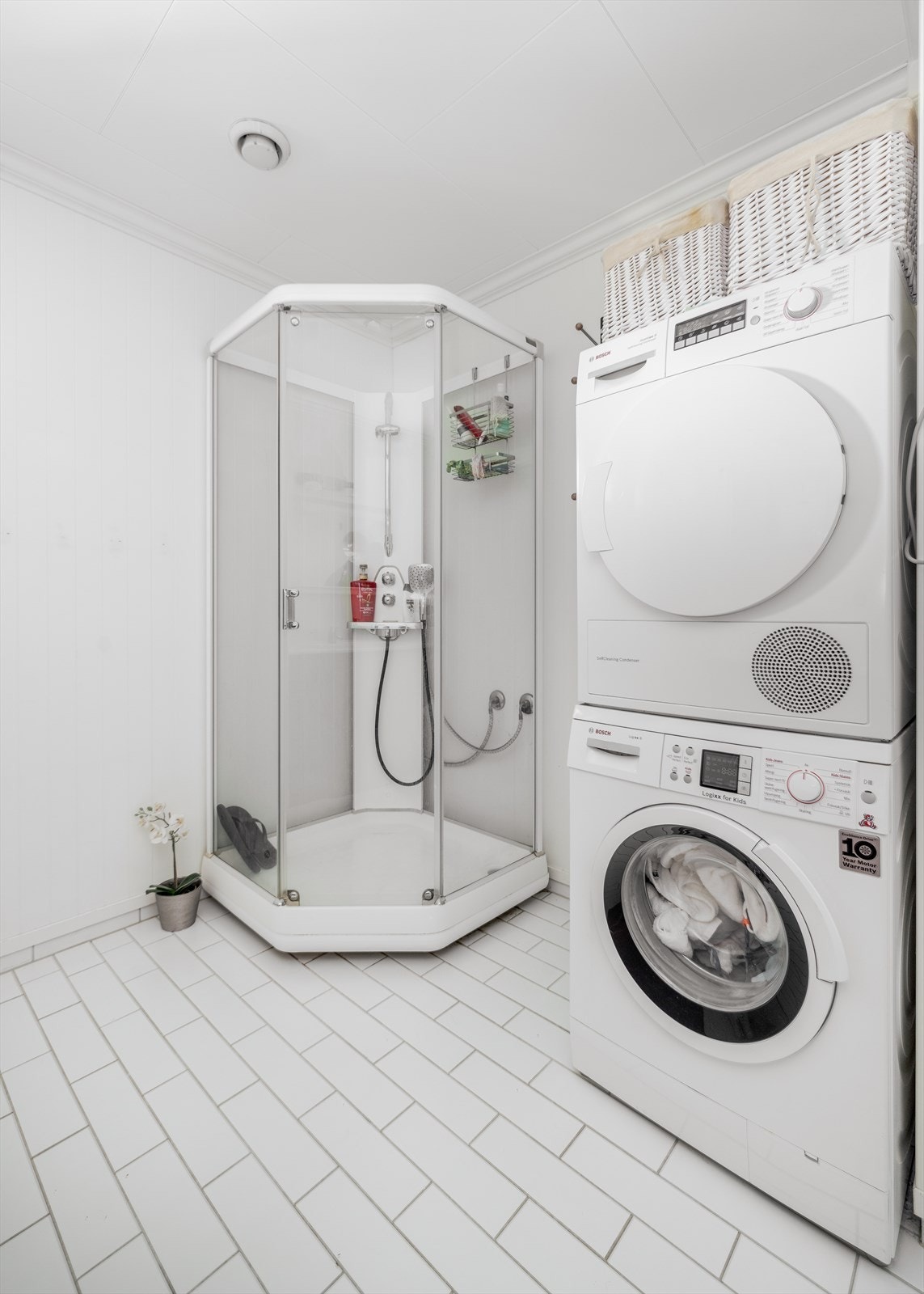 Det er også etablert opplegg for vaskemaskin. Overflater består av flis på gulv og hvitmalte panelplater på vegger. Takessplater i tak. Galleribilde