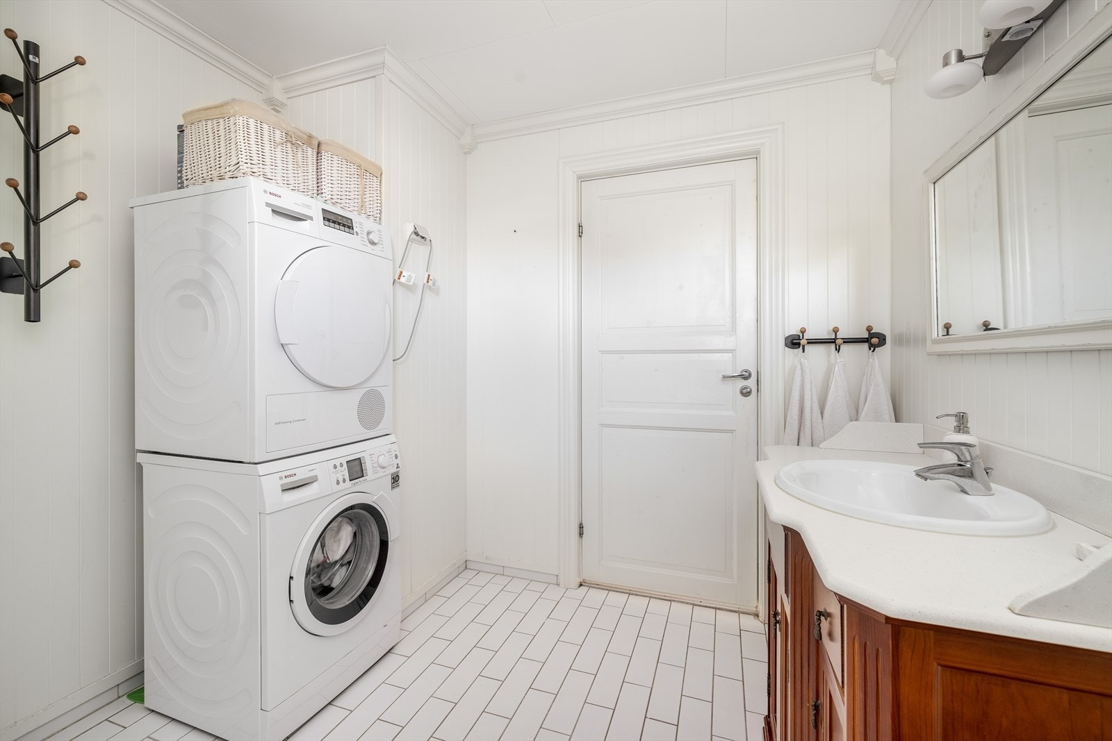 Romslig servantinnredning med skuffer og skap, samt benkeplate med nedfelt servant. Speil og overlys på vegg. Galleribilde