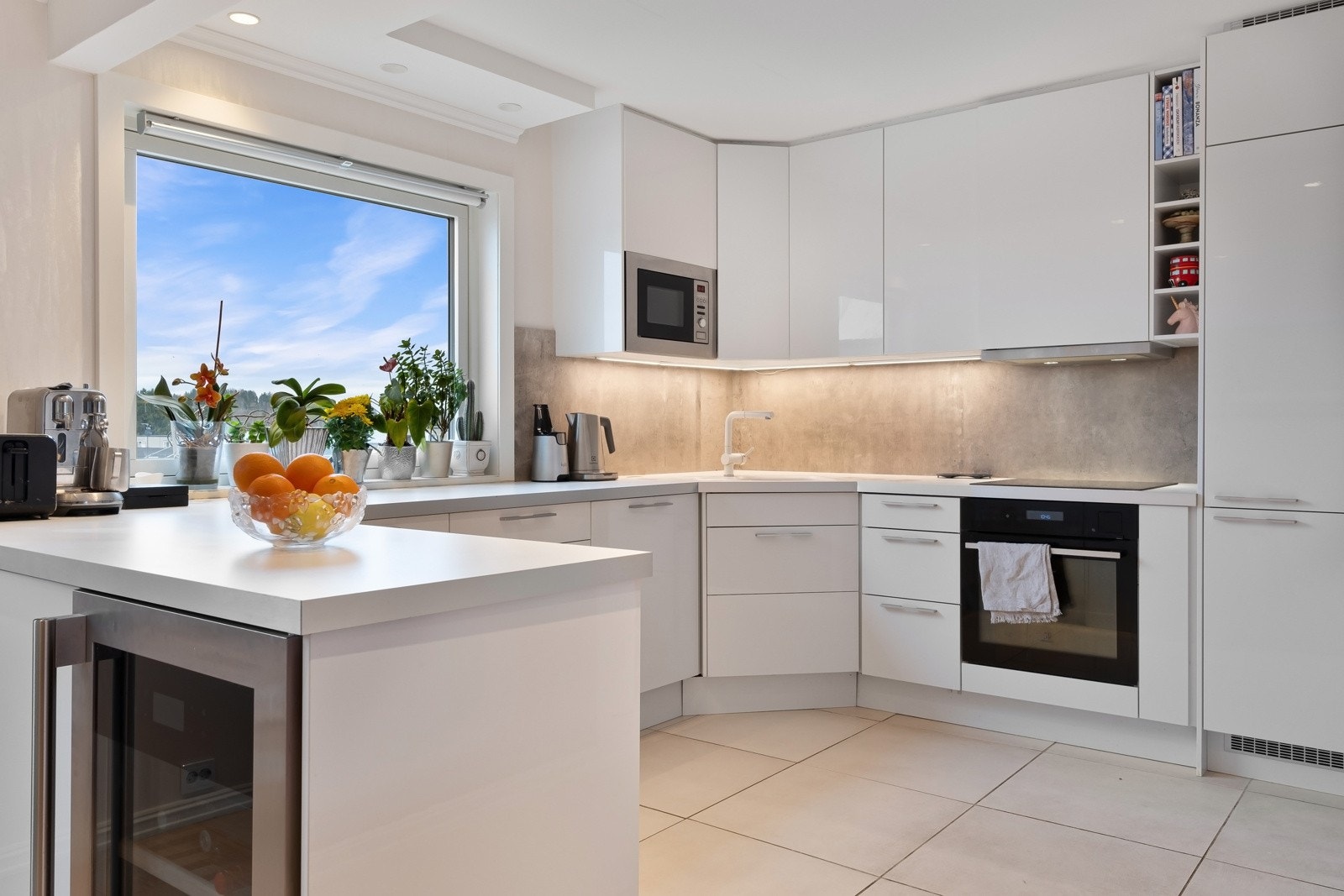 Innredningen består av hvite slette høyglansede skuffe- og skapfronter og laminert benkeplate med nedfelt vaskekum m/ettgreps blandebatteri. Det er satt inn moderne Kitchenboards mellom over- og underskap, samt belysning. Galleribilde