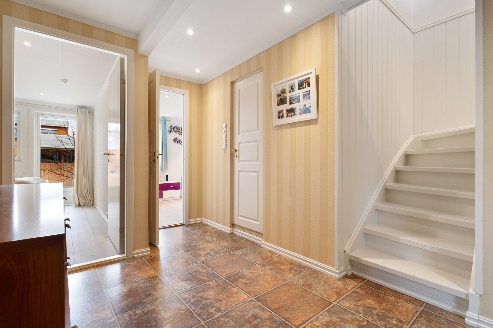 Tiltalende entre/hall i boligens 1. etasje med lyse veggflater og flisimitert vinyl på gulv med gulvvarme. Galleribilde