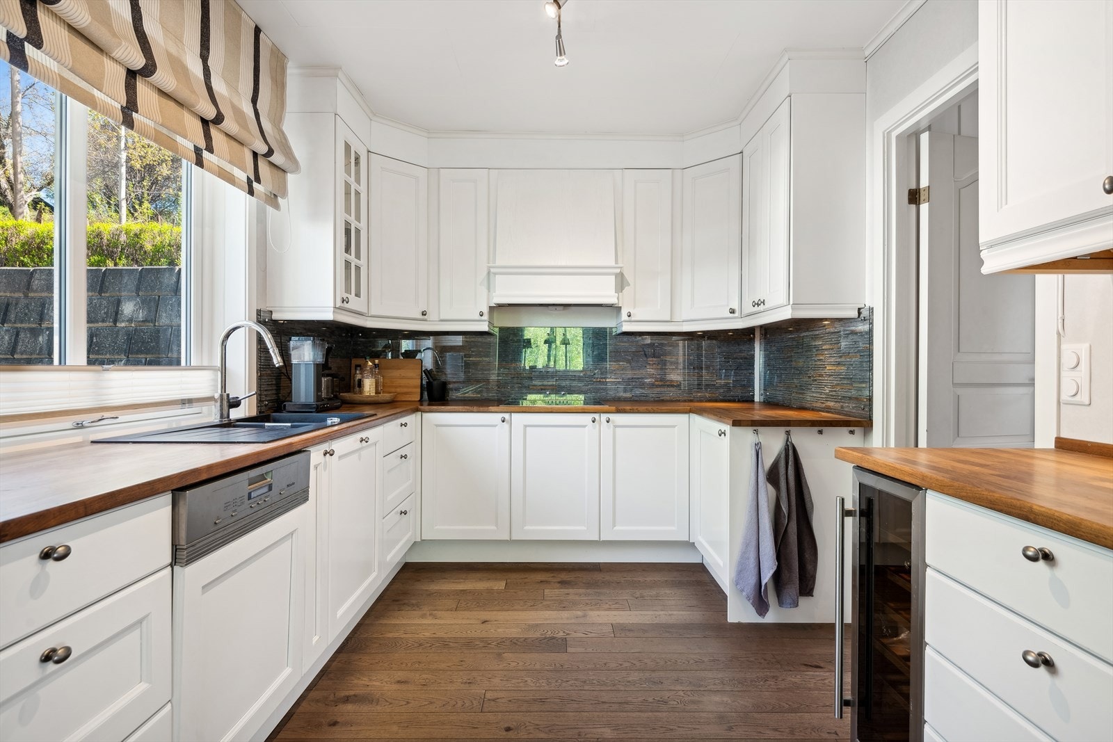 Innredningen har hvite, profilerte fronter og heltre benkeplate med dobbel kjøkkenkum. Galleribilde