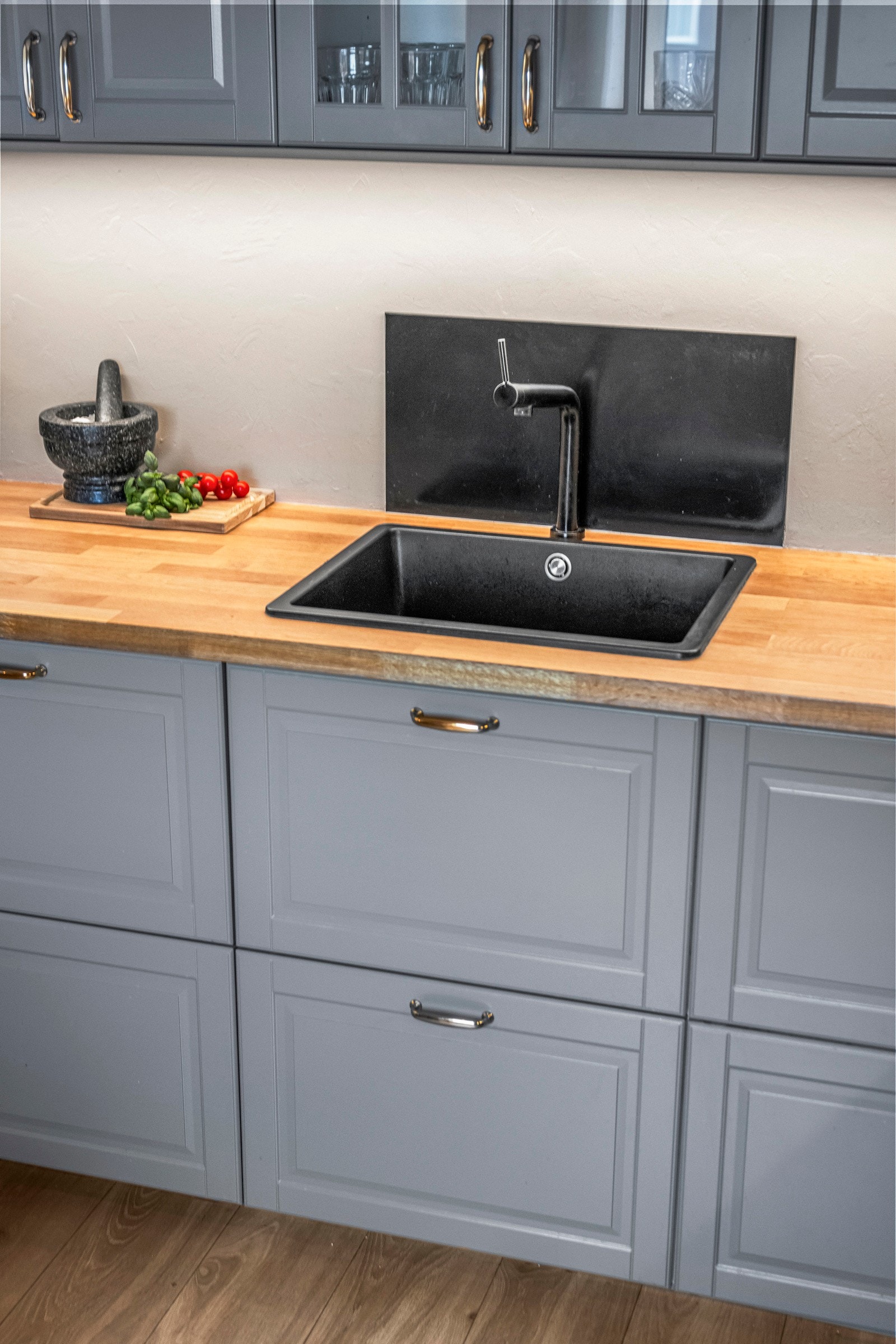 Innredningen har profilerte fronter, to vitrinedører, dempefunksjon og benkeplate i eikefarget laminat med vaskekum i sort kvartskompositt. Galleribilde