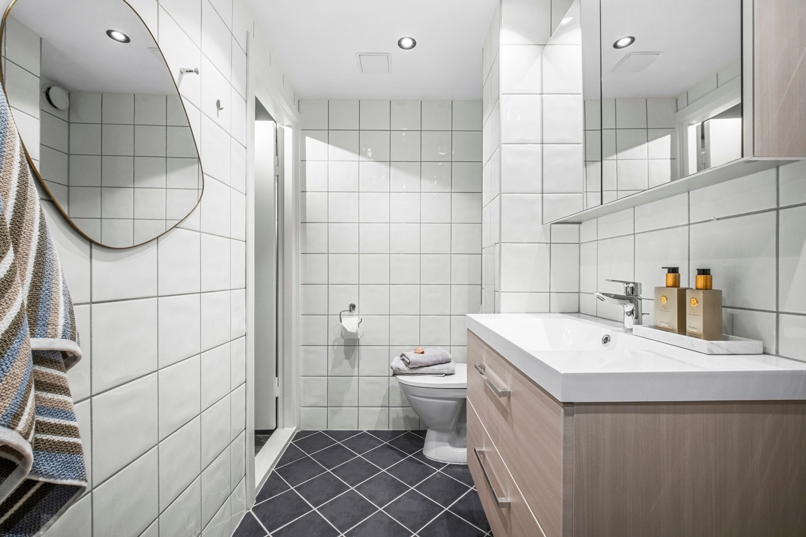 Innredningen består av en heldekkende servant på lys, eikefarget skuffeseksjon, speilskap og et toalett. Galleribilde