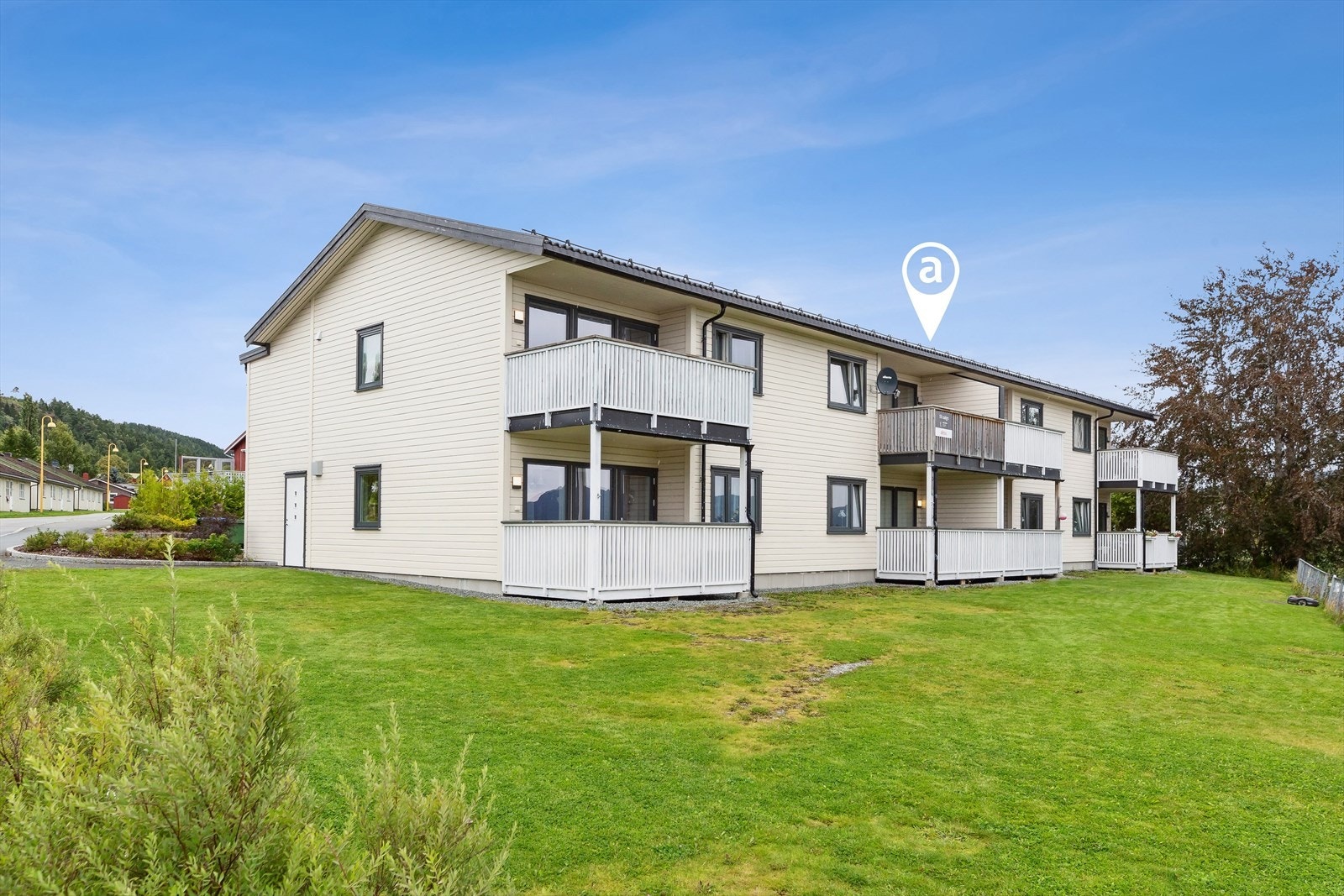 En moderne og innbydende bolig fra 2017, omkranset av landlige omgivelser og med en asfaltert gårdsplass for parkering. Galleribilde