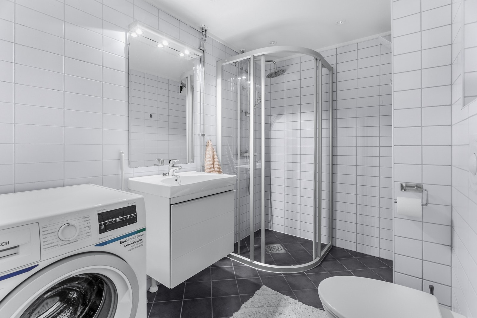 Badet er fra 2007 og har et klassisk og tidløst uttrykk med hvite fliser på veggene og sorte fliser på gulvet. Elektriske varmekabler sørger for komfortabel varme under føttene. Galleribilde