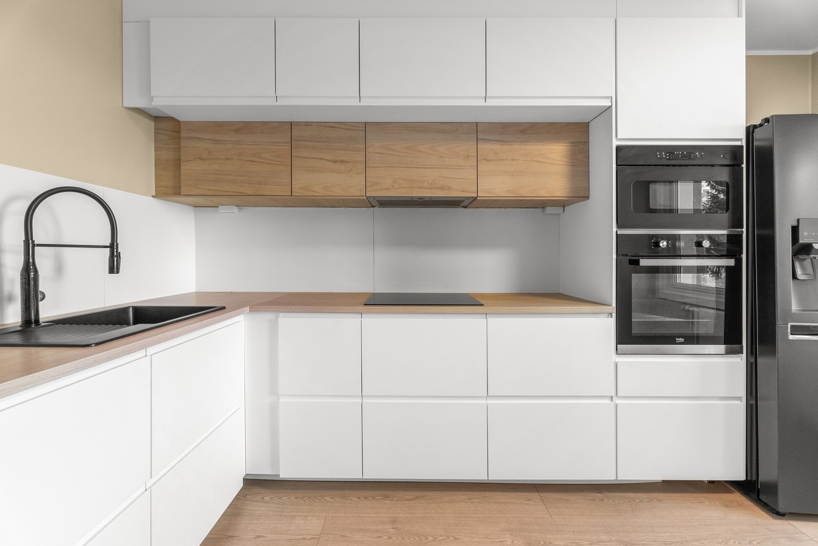 Kjøkkenet er både funksjonelt og gjennomført med et moderne design. Hvite, glatte fronter kombineres med stilige detaljer i sort og tremateriale. Galleribilde