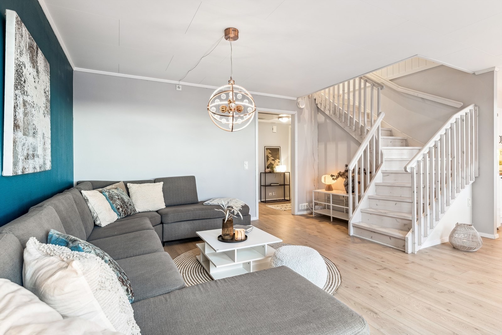 Leiligheten har en lys og romslig stue med trapp opp til loftsetasje Galleribilde