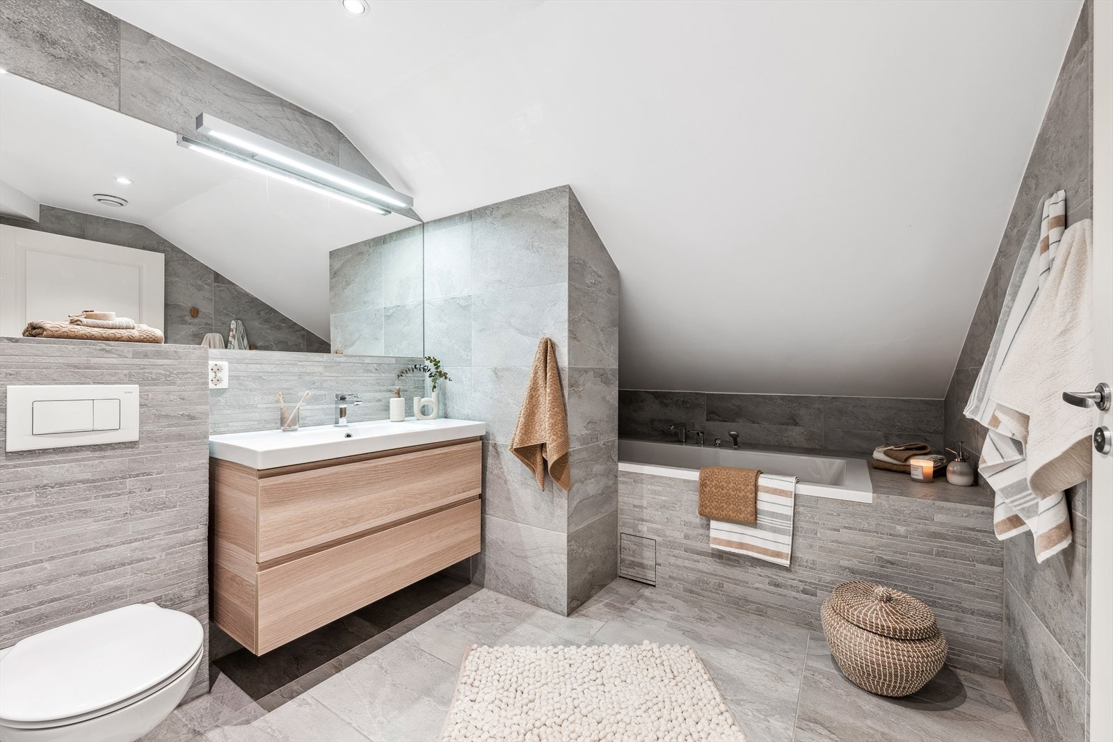 Delikat og stilig flislagt bad fra 2018 med vegghengt wc, badekar og flott innredning med servant. Galleribilde