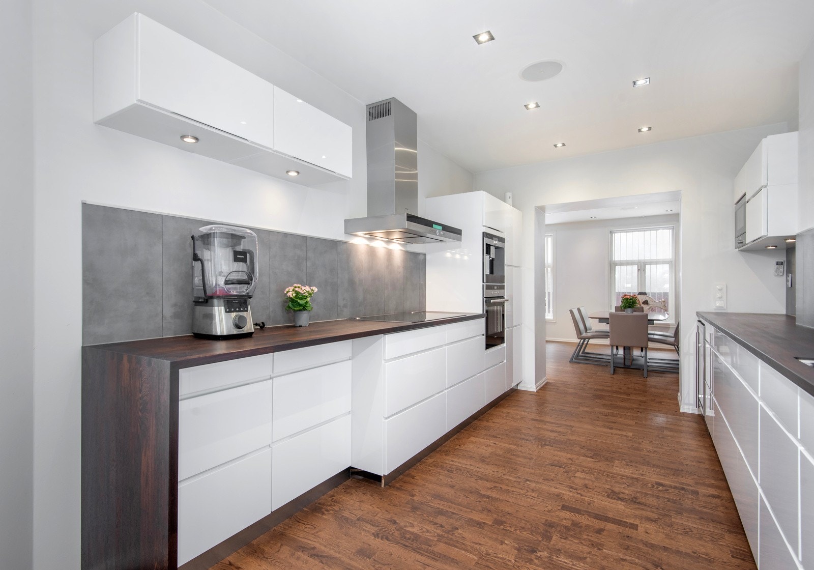 Innredning med hvite høyglans fronter og fliser på vegg over heltre mørk benkeplate. Galleribilde