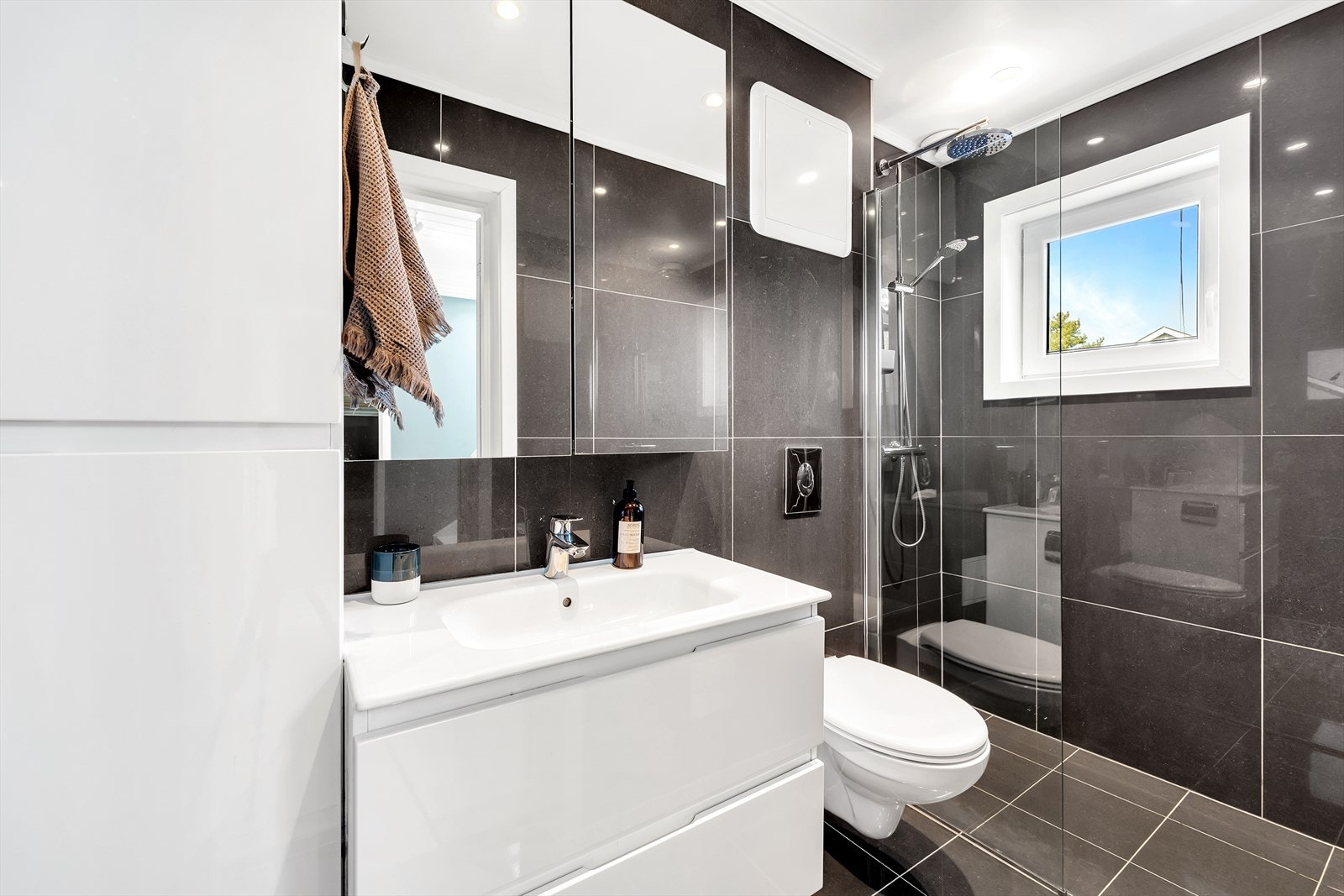 Pent nyere bad fra 2018 med fliser på gulv og vegger, malt tak med downlights. Innredningen består av dusjnisje med glassvegg, heldekkende servant med underskuffer, overskap med speilfronter, veggskap, vegghengt wc og varmekabler i gulv. Galleribilde