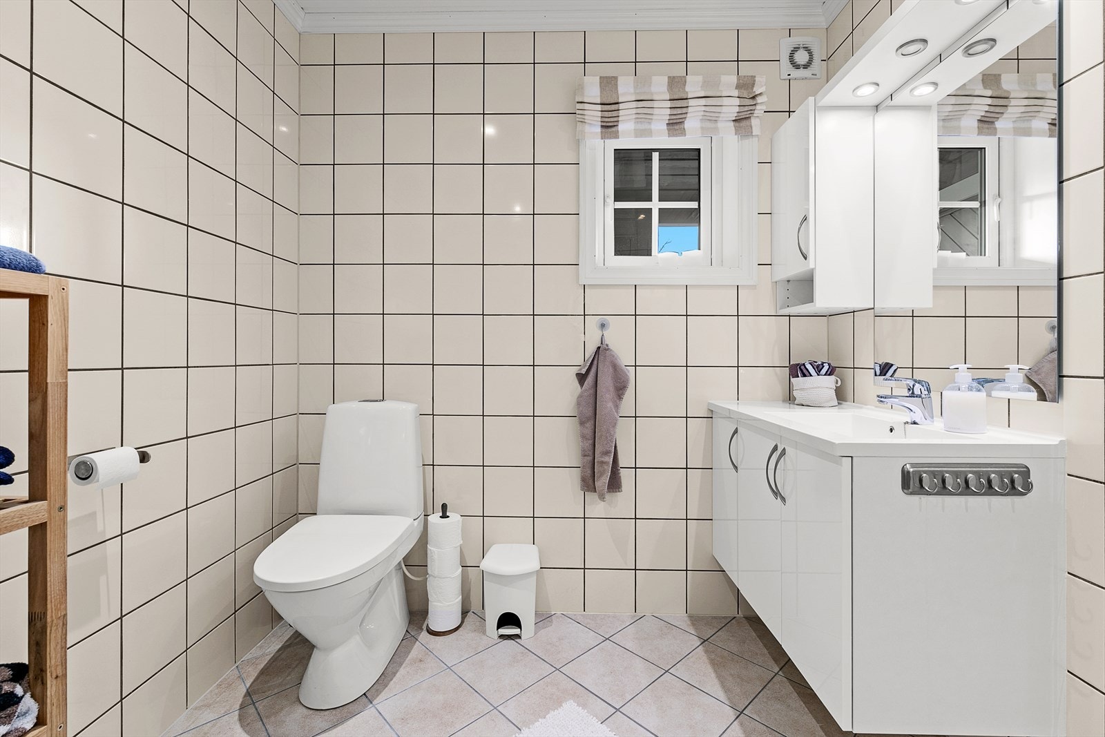 Badet innehar wc, dusjkabinett og servant. Opplegg for vaskemaskin. Her er det fliser på gulv og vegger. Galleribilde