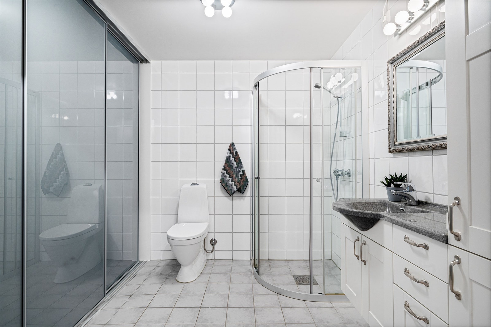 Bad kombinert vaskerom har flis på gulv og vegger. Det er vannbåren varme i gulv. Galleribilde