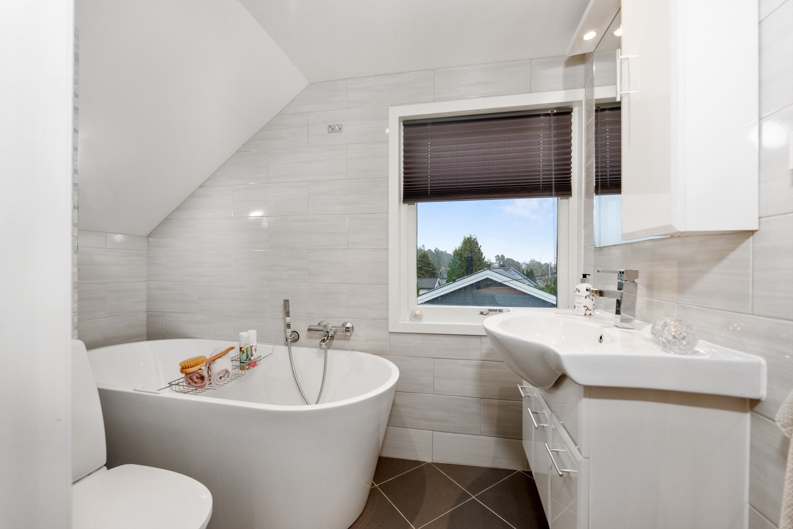 Badet i 2. etg har lyse fliser på vegg kombinert med mørke gulvfliser, gulvvarme og badekar til glede for liten og stor. Galleribilde