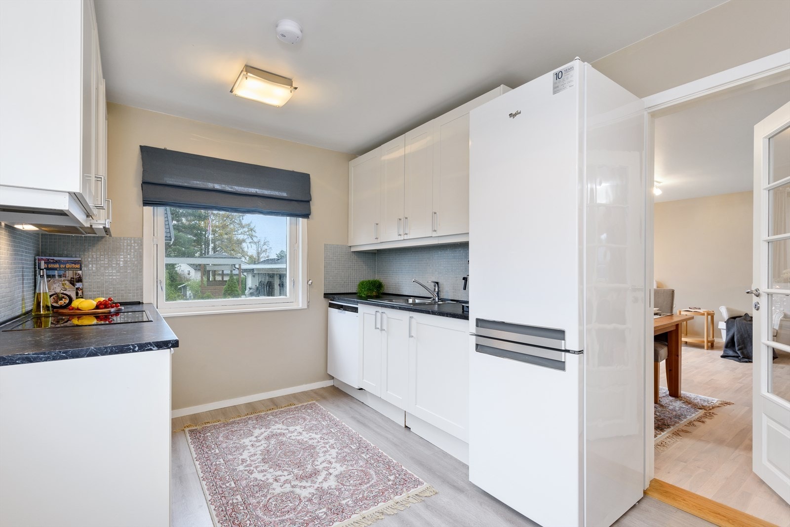 Innredningen er funksjonelt plassert parallelt på to vegger, med hvite, rettprofilerte fronter og benkeplate i laminat. Galleribilde