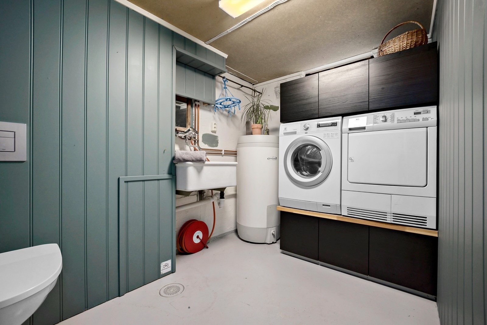 I tillegg til mye god bodplass i kjelleren er det også vaskerom. I rommet er det innredning med plass til vaskemaskin og tørketrommel, slik at disse kommer opp i god arbeidshøyde. I rommet er det også varmtvannsbereder, skyllekar og toalett. Galleribilde