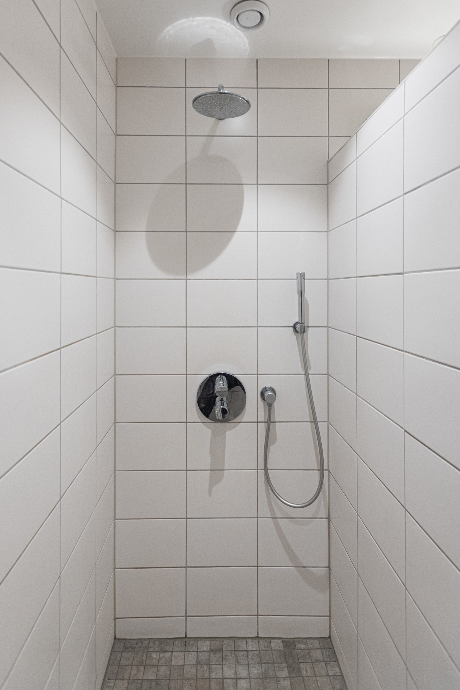 Badet er innredet med servant, veggmontert toalett og dusj. Galleribilde