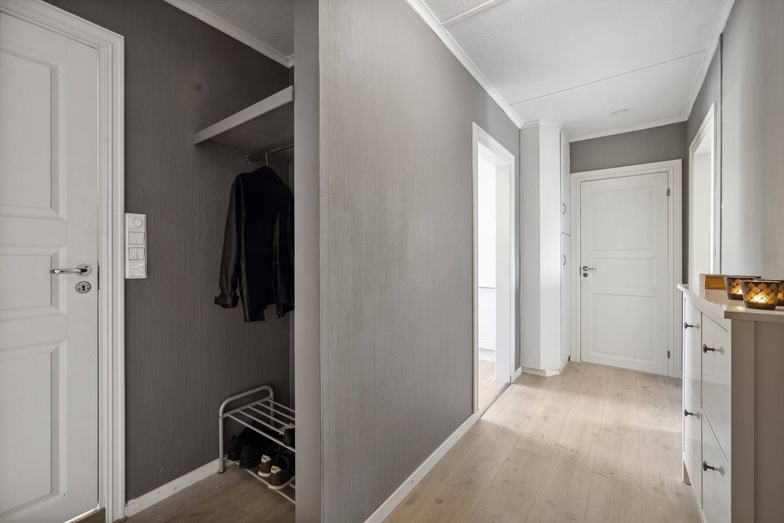 Innvendig mottas du av en avlang entré med lyst laminatgulv og gråmalte vegger. Entréen har et eget hjørne med plass til å henge fra seg yttertøy og sko Galleribilde
