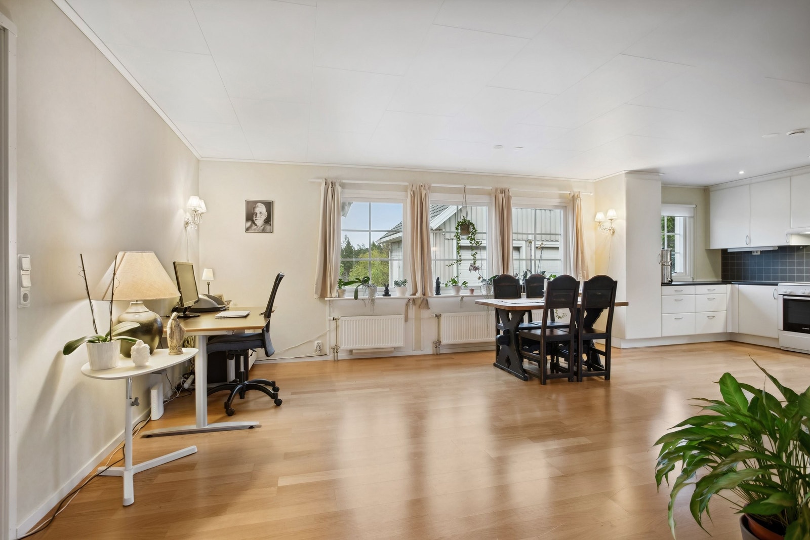 Romslig stue med ulike muligheter, her kontorplass i hjørnet og spiseplass nærmere kjøkkenet Galleribilde