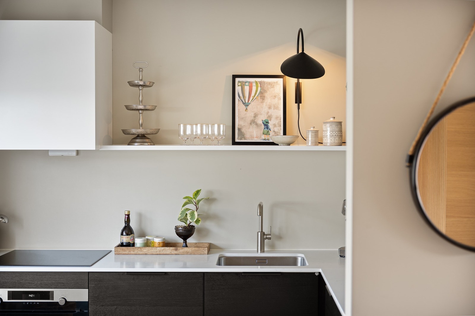 Den åpne hyllen viser frem dekorative elementer, samtidig som den holder viktige kjøkkenartikler lett tilgjengelige. Benkeplaten er stein fra Silestone og gir rikelig med arbeidsplass. Galleribilde