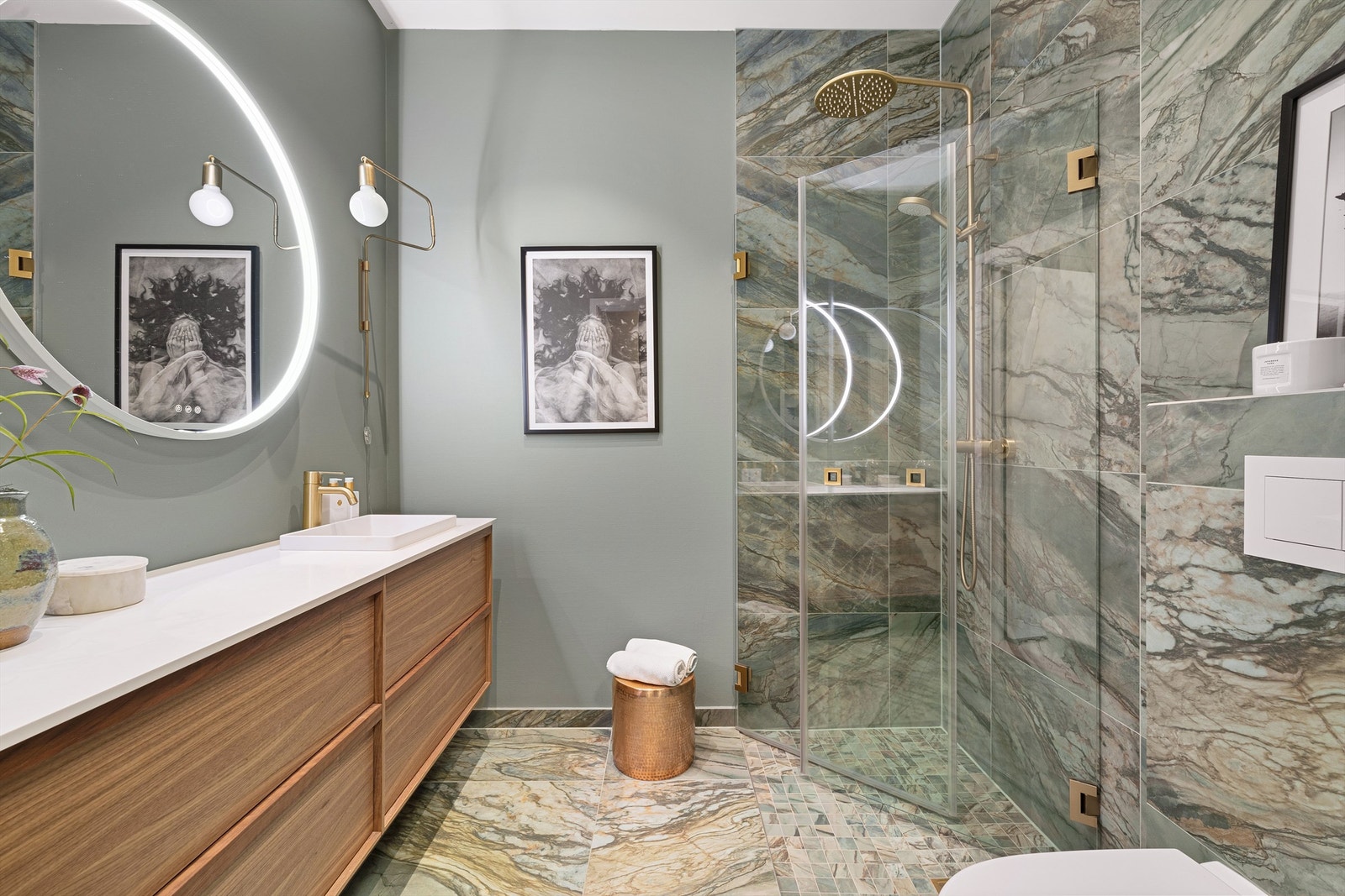 Dette badet utstråler luksus og moderne eleganse. Dusjsonen er innrammet av glassvegger, og detaljer i messing tilfører en sofistikert og innbydende atmosfære. Galleribilde