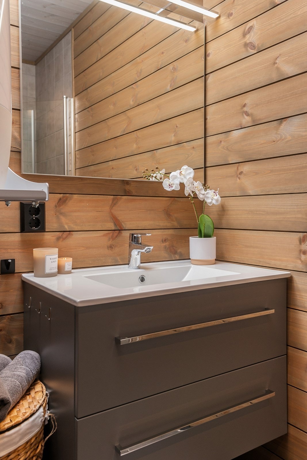 Baderomsinnredningen er pent utført med grå, glatte fronter med romslige skuffer og heldekkende servant. Galleribilde