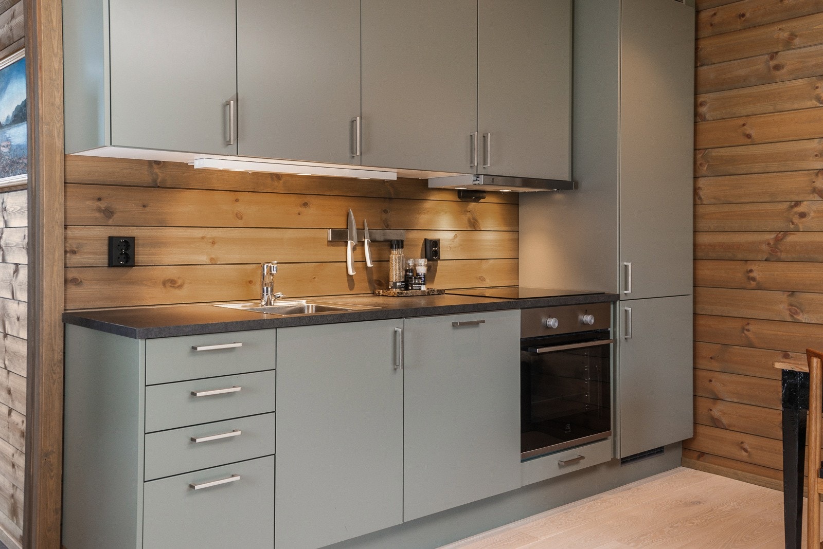 Kjøkkeninnredningen er pent utført med lysegrå, glatte fronter og laminert benkeplate med kjøkkenkum. Galleribilde