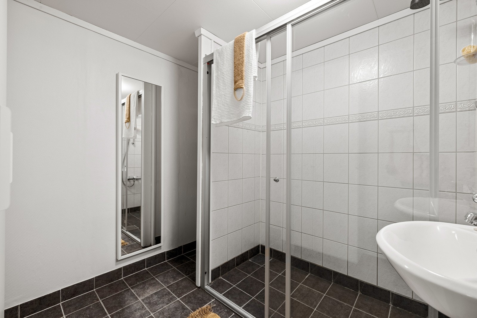 Badet er innredet med dusj med skyvedør, servant og opplegg for vaskemaskin. Galleribilde